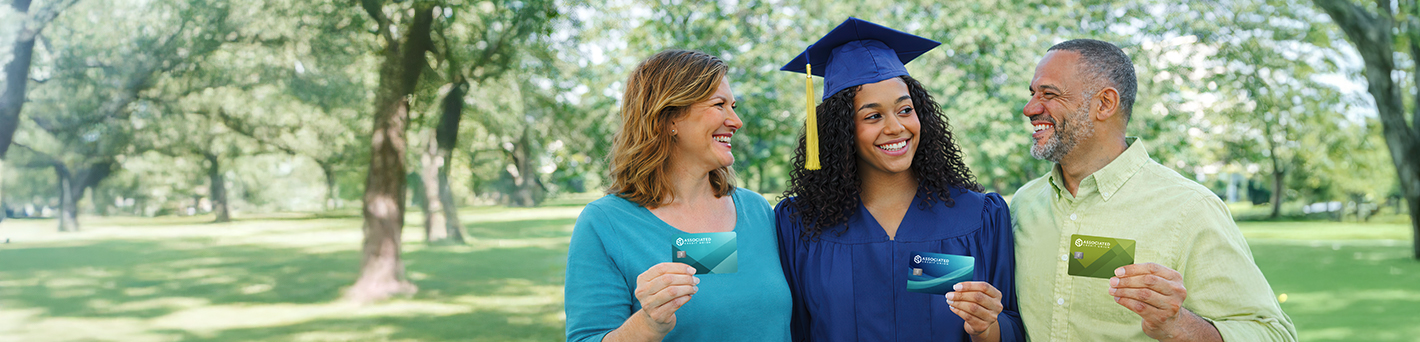 Parents with their graduate daughter, all holding ACU VISA gift cards and smiling