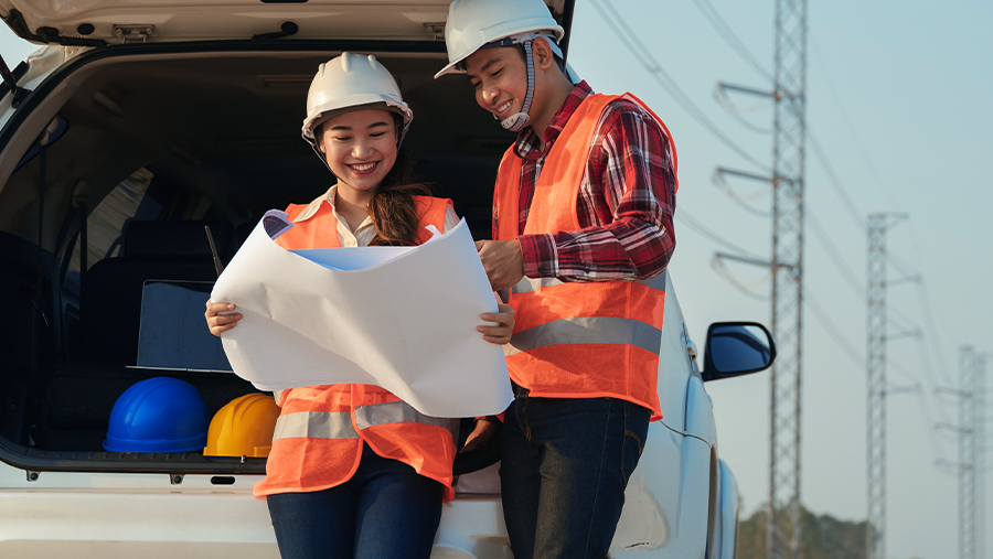 Man and woman with hard hats in van looking at blueprints