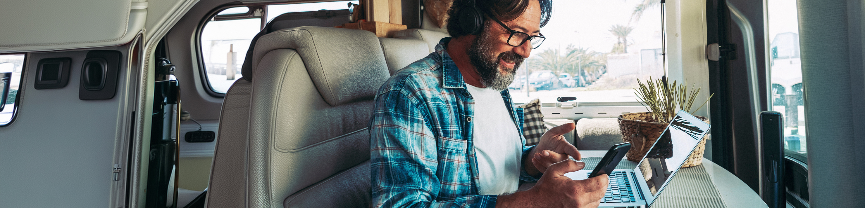 Man in RV doing work tasks on his phone and laptop