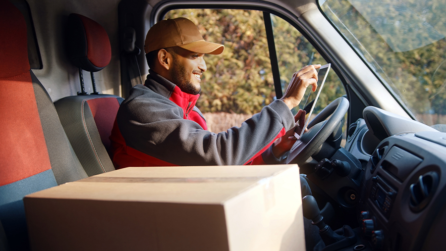 Man smiling while driving in van with box
