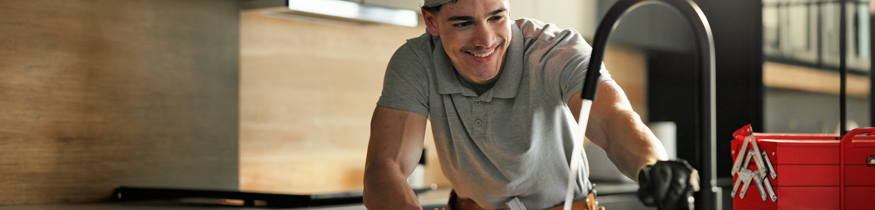 Man with a moustache smiling while working on the sucessful plumbing of a sink
