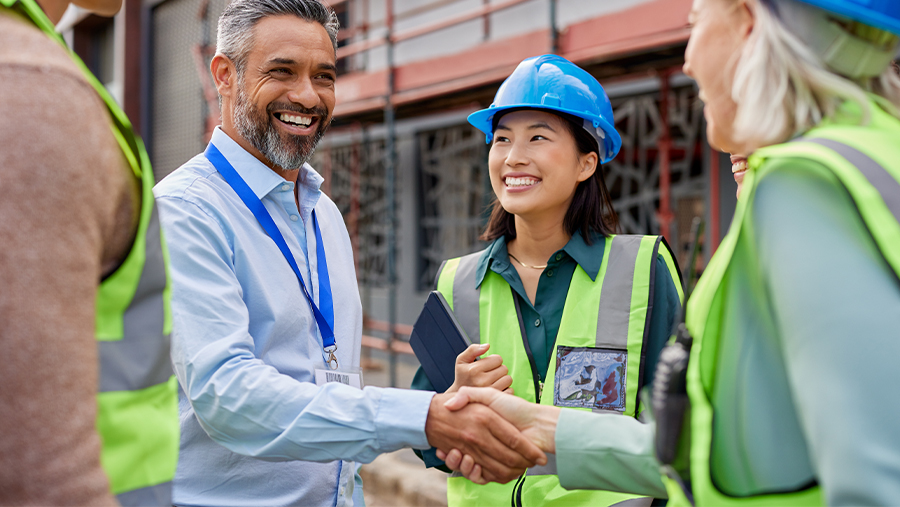People with hard hats smiling at a man with a badge