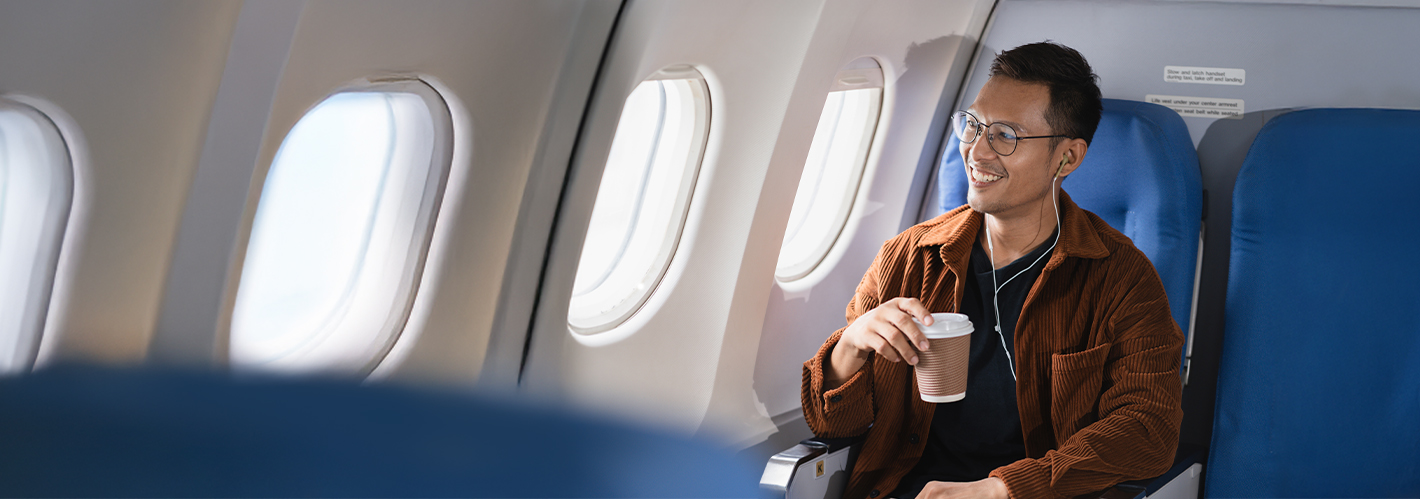 smiling man on a plane with a coffee