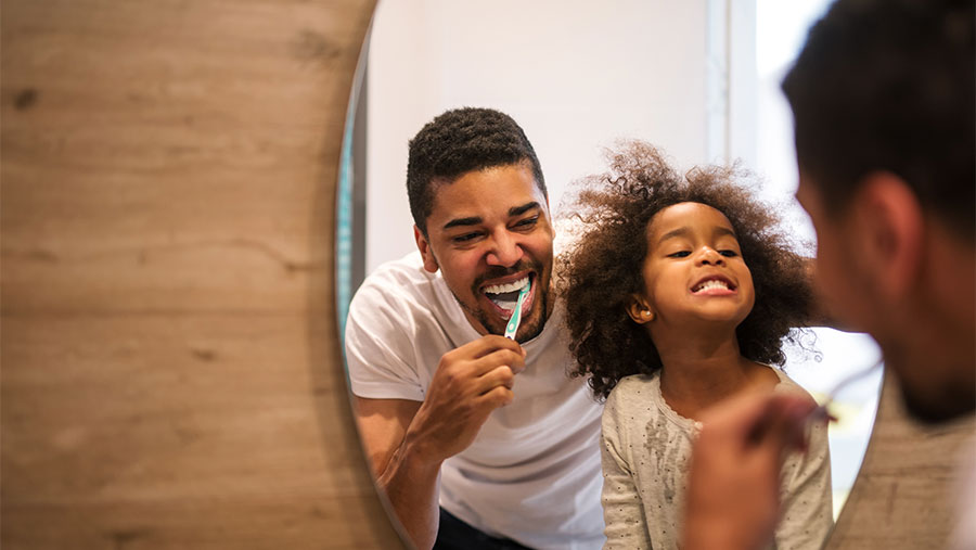 Father and daughter brushing their teeth
